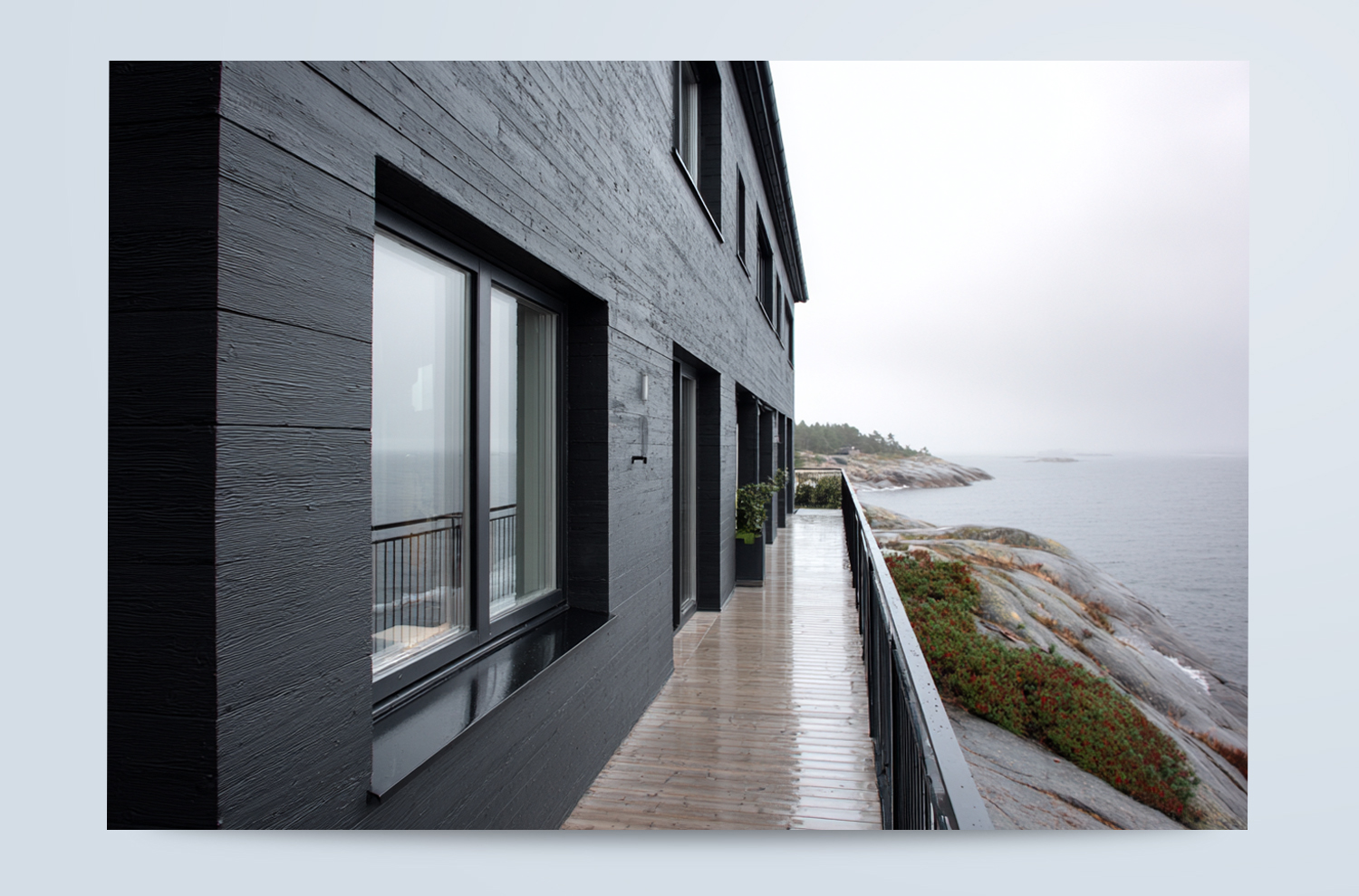 Inspiration för svartmålad träfasad vid havet Modern svartmålad träfasad med stora fönster och terrass i kustnära miljö.